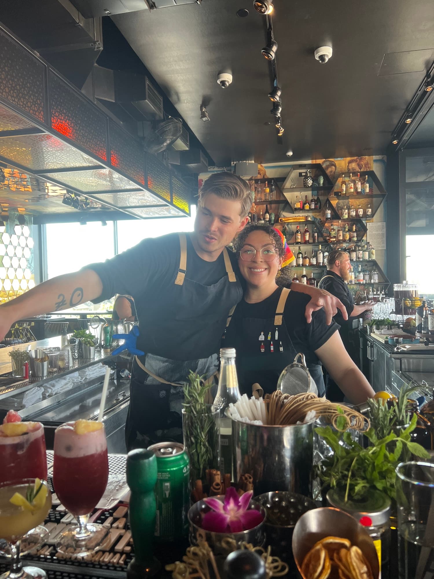 Austin O'Neil behind the bar in Denver, arm around a coworker, both in aprons